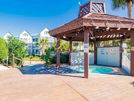 A covered outdoor area with a pool, wooden pergola, and a gated entrance.