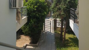A narrow pathway leading to a residential building with a tiled roof, surrounded by greenery and a clear sky. - Dream Cottage Nikiti Greece (Sithonia)