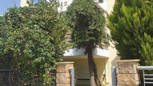A two-story residential building with a balcony, stone walls, and a gate. - Dream Cottage Nikiti Greece (Sithonia)
