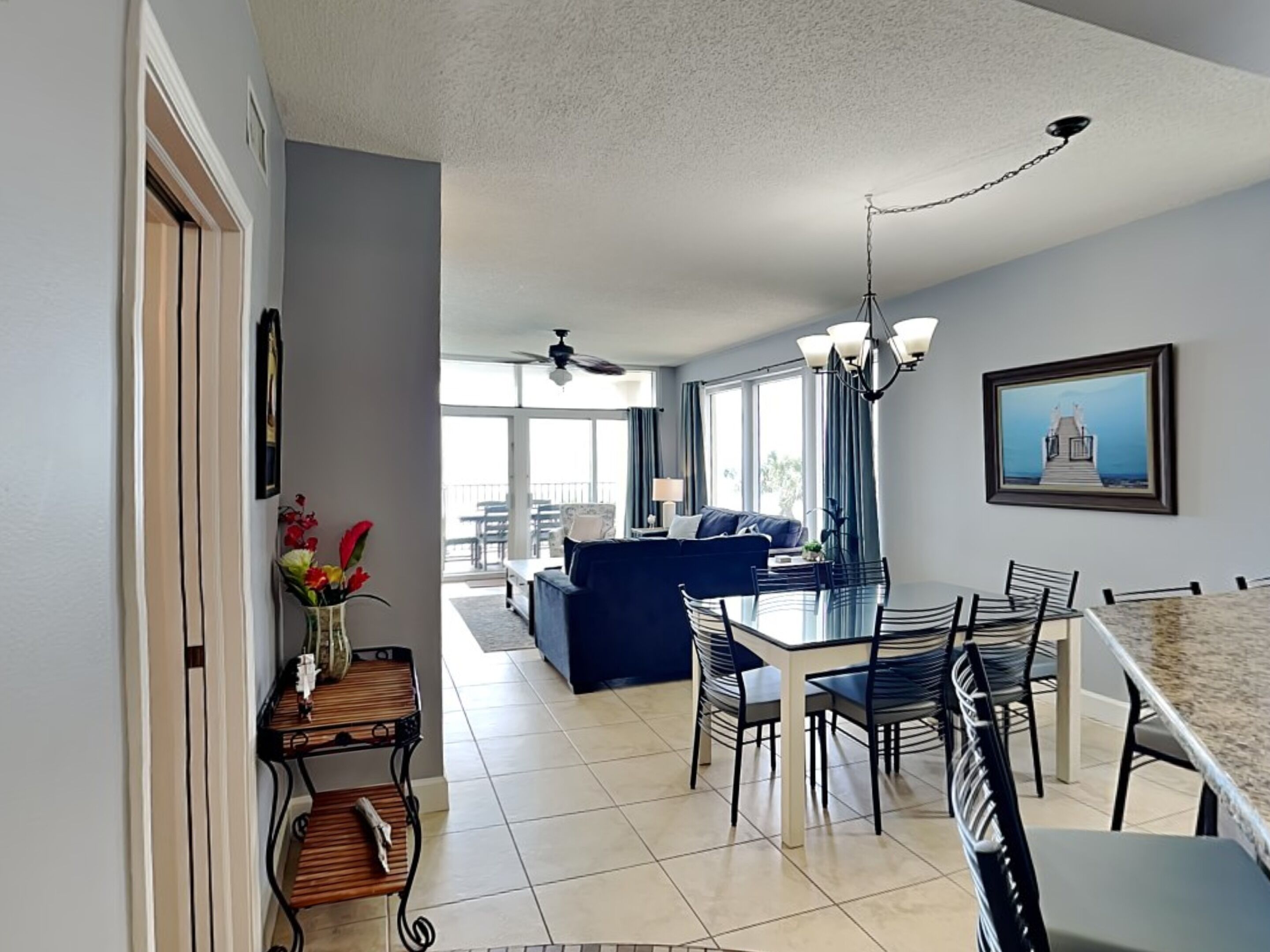 A modern kitchen with a dining area, a ceiling fan, and a large window providing natural light.