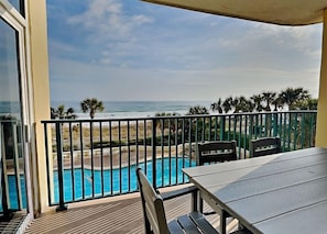 Enjoy a peaceful view of the ocean from this balcony, featuring a table and chairs for dining or relaxation.