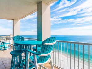 A balcony with turquoise chairs and a table, overlooking a beach and ocean. - Island Towers by Southern Vacation Rentals (Gulf Shores)