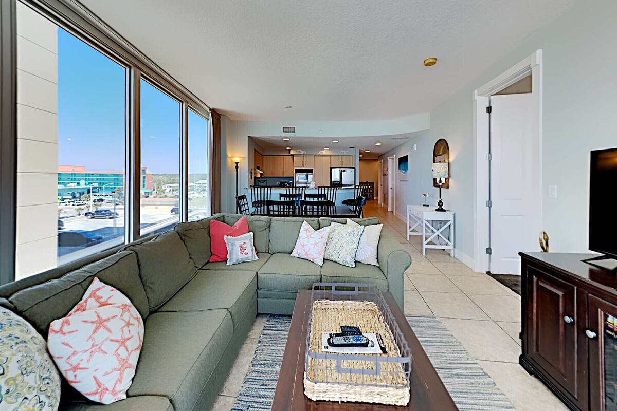 A living room with a large window, a sofa, a coffee table, and a TV.
