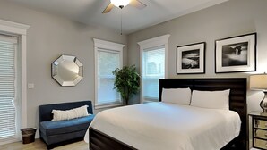 A bedroom with a large bed, a dark headboard, a blue sofa, and a ceiling fan. - Miramar Beach Villas by Southern Vacation Rentals (Miramar Beach)