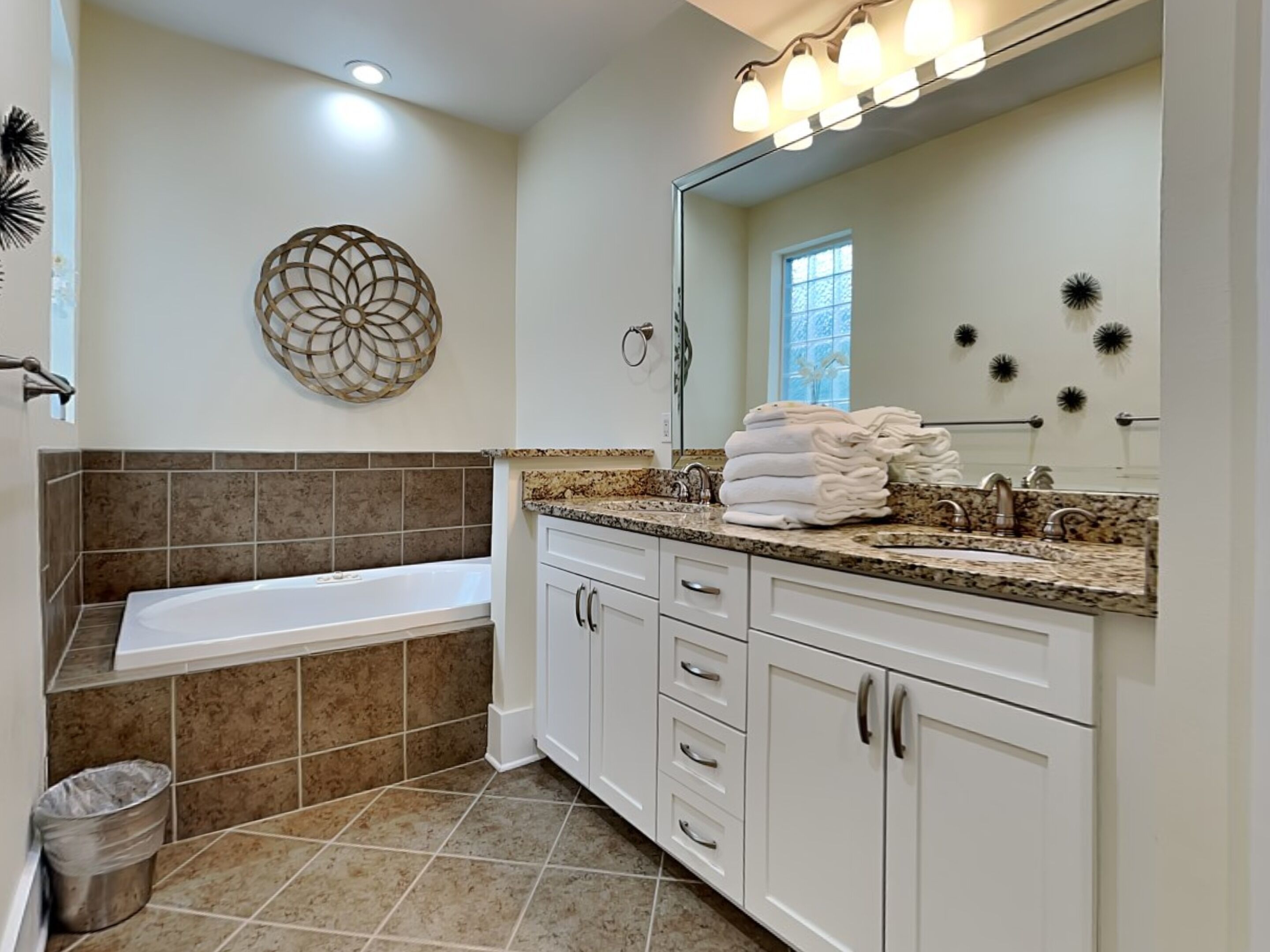 A modern bathroom with a bathtub, white cabinetry, and a vanity with a sink.