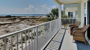 A balcony with wicker chairs overlooking a beach with sparse vegetation and a clear sky. - Gulf Island by Southern Vacation Rentals (Navarre)