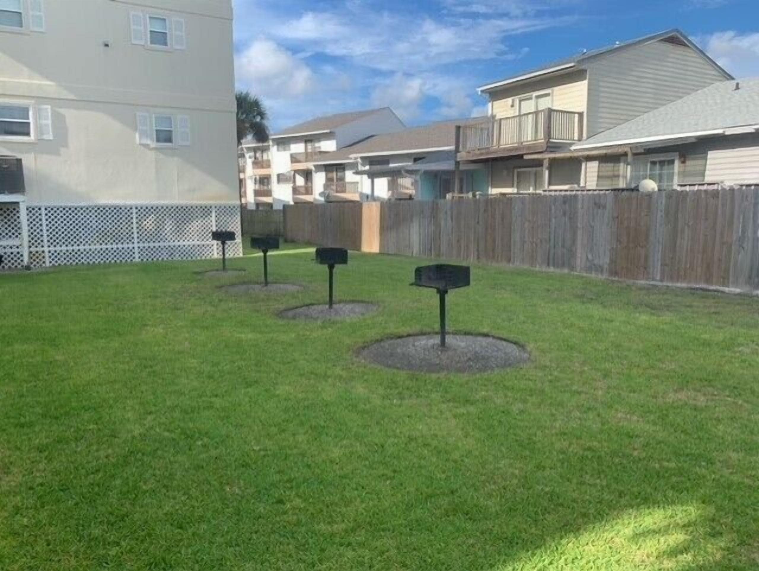 A grassy yard with four mailboxes and a wooden fence.