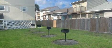 A grassy yard with four mailboxes and a wooden fence.
