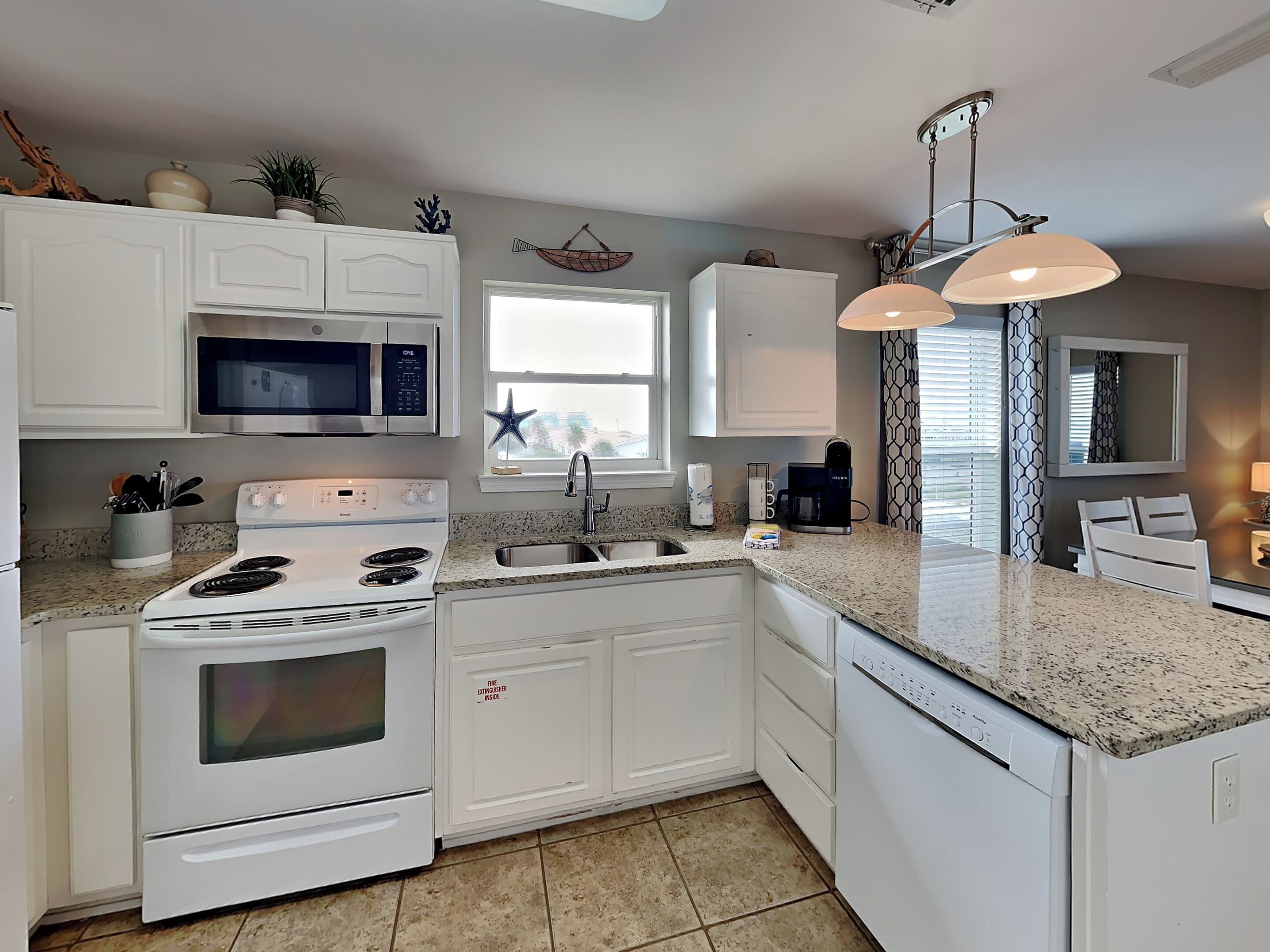A modern kitchen with white cabinetry, a microwave, stove, and a coffee maker.