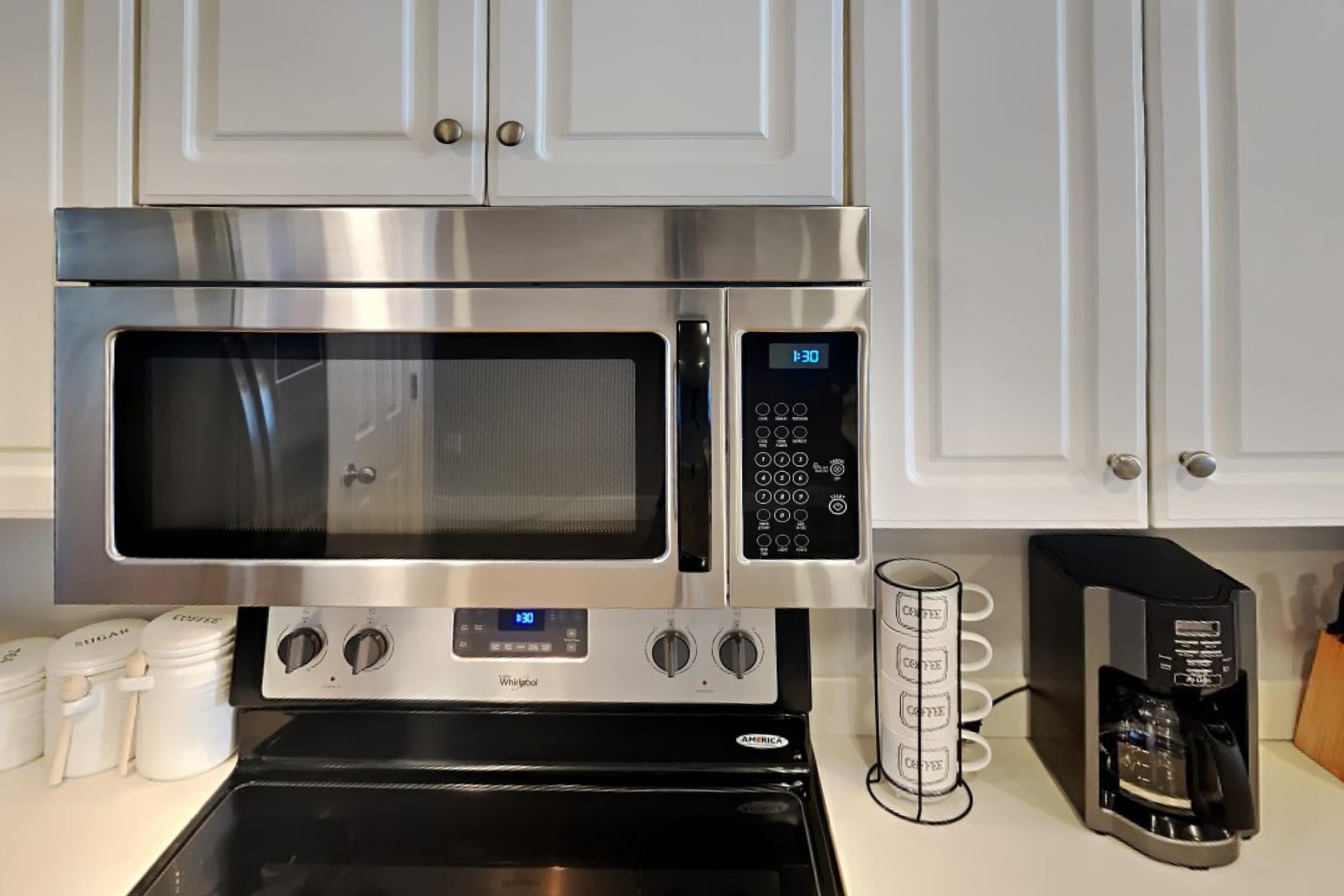 Una cocina con microondas de acero inoxidable, horno Whirlpool y cafetera.