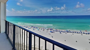 A beach view from a balcony with a railing, clear blue sky, and turquoise sea. - Majestic Beach Towers II by Resort Collection (Panama City Beach)