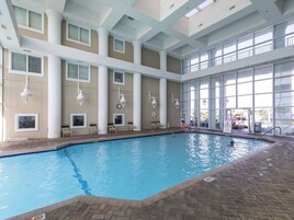 Una piscina interior con agua azul cristalina, rodeada por un suelo de baldosas y un borde de ladrillo.