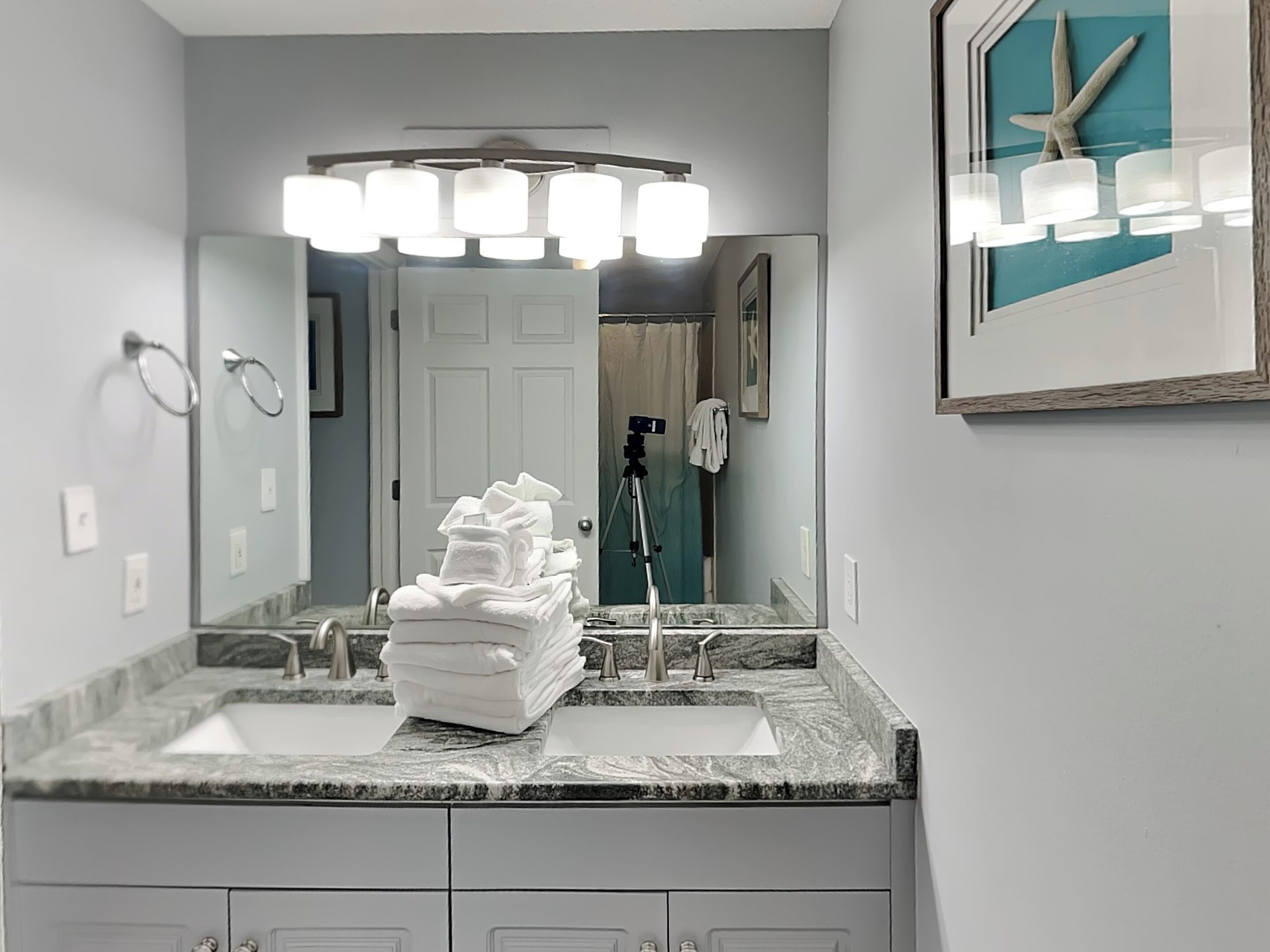 A bathroom with two sinks, a large mirror, and a starfish decoration.