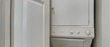 A stacked washer and dryer unit with a notice label on the top.
