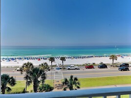 Una playa de arena blanca, sombrillas azules y palmeras.