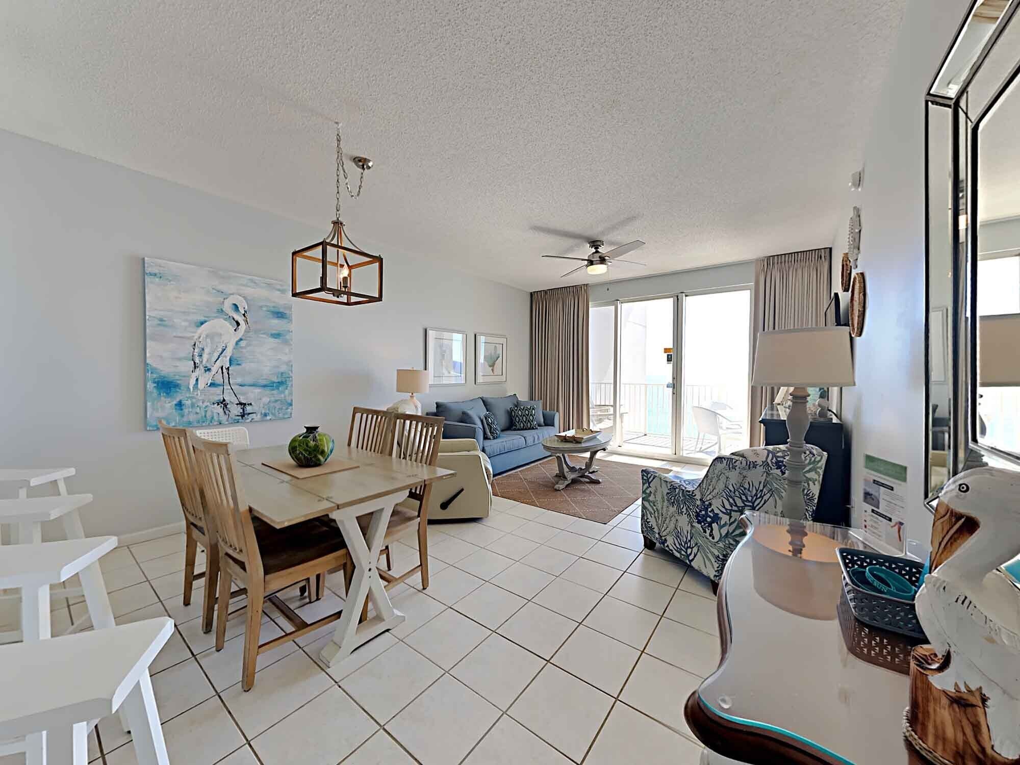 A spacious living area with a dining table, chairs, a sofa, and a ceiling fan.