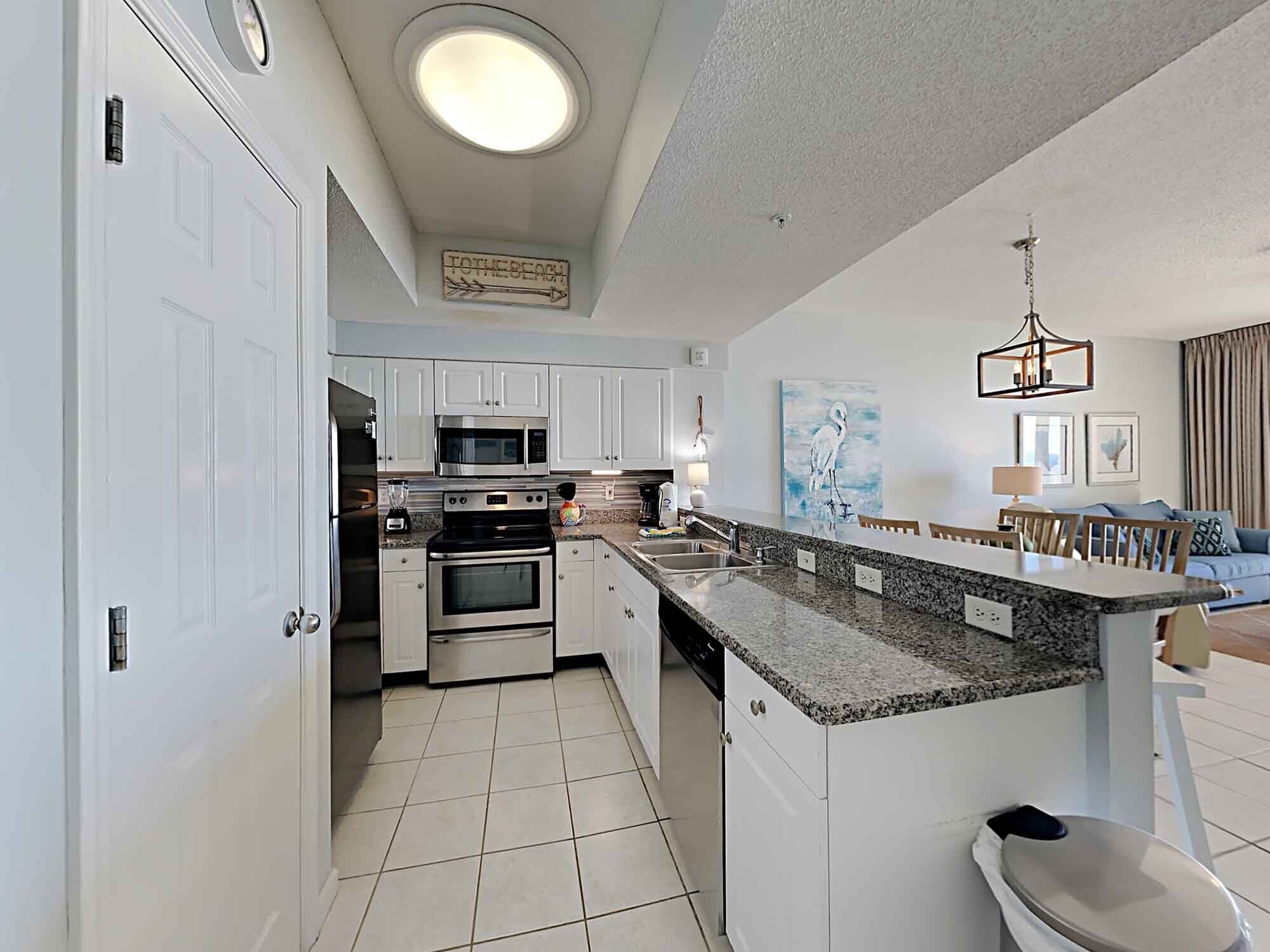 A modern kitchen with white cabinets, stainless steel appliances, and a granite countertop.
