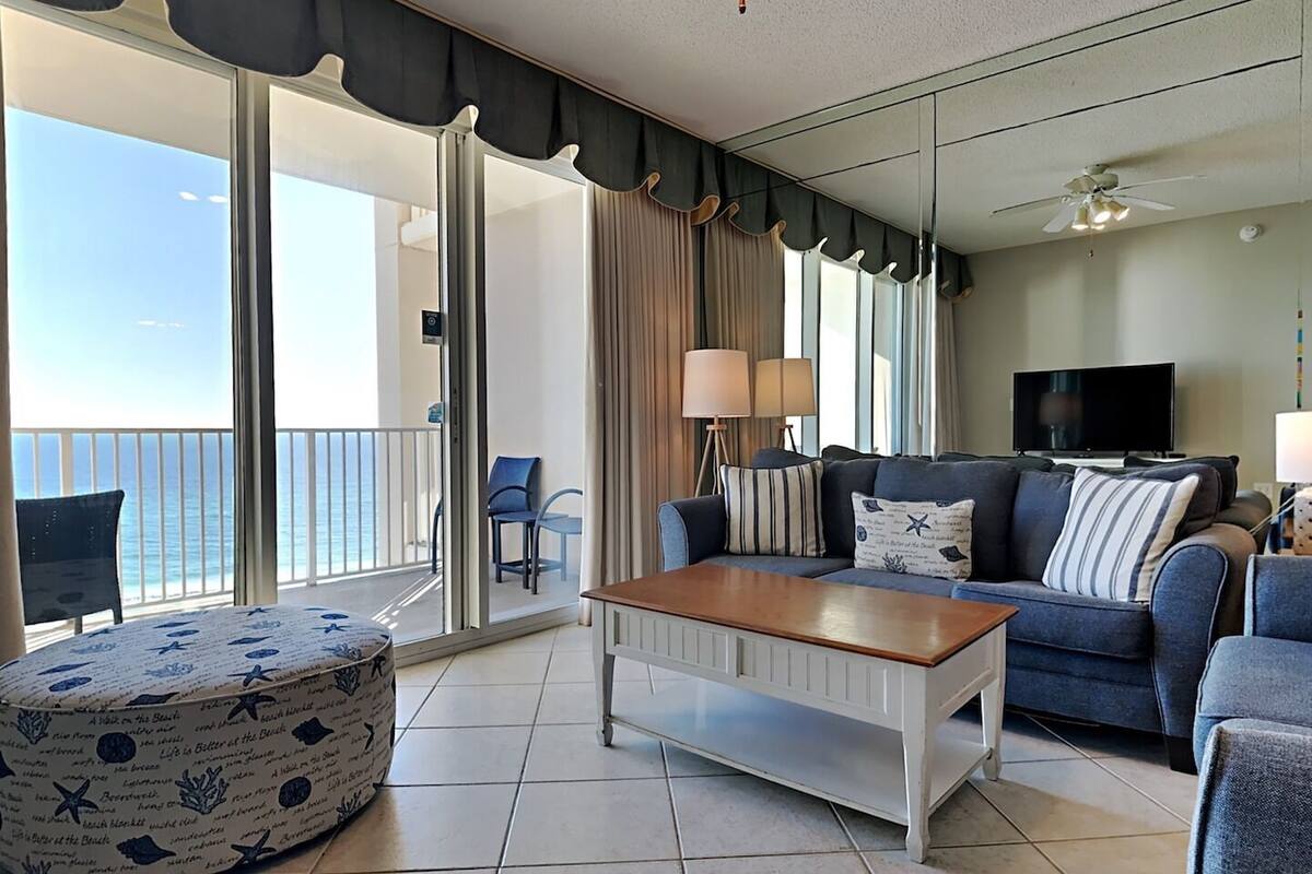 A living room with a sofa, a coffee table, and a view of the ocean.