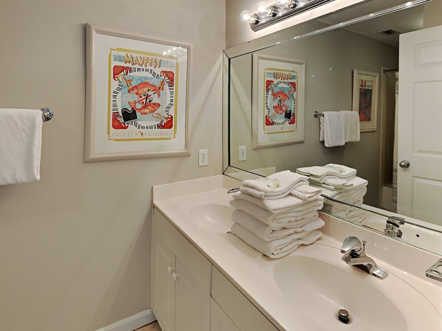 A bathroom with a sink, mirror, and two framed posters on the wall.