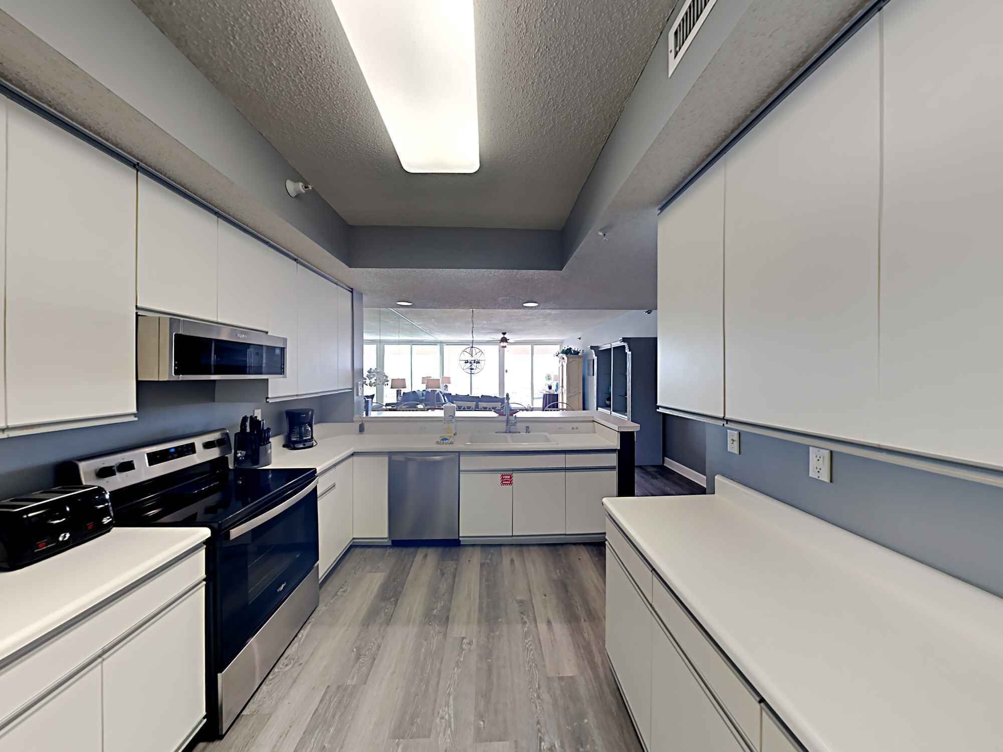 A modern kitchen with white cabinets, a black stove, and a central island with a sink.