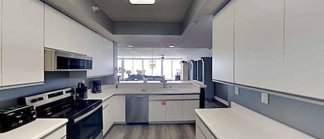 A modern kitchen with white cabinets, a black stove, and a central island with a sink.