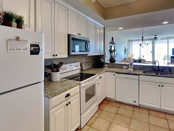 A kitchen with white cabinets, a stainless steel refrigerator, a microwave, and an oven.