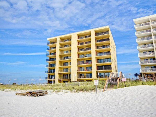 Un hôtel à plusieurs étages, doté de balcons, situé près d’une plage.