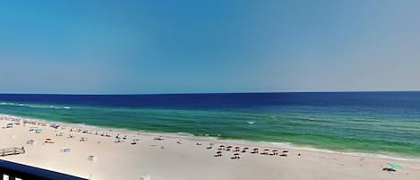 Una spiaggia con vista libera sull'oceano e un balcone affacciato sulla spiaggia.