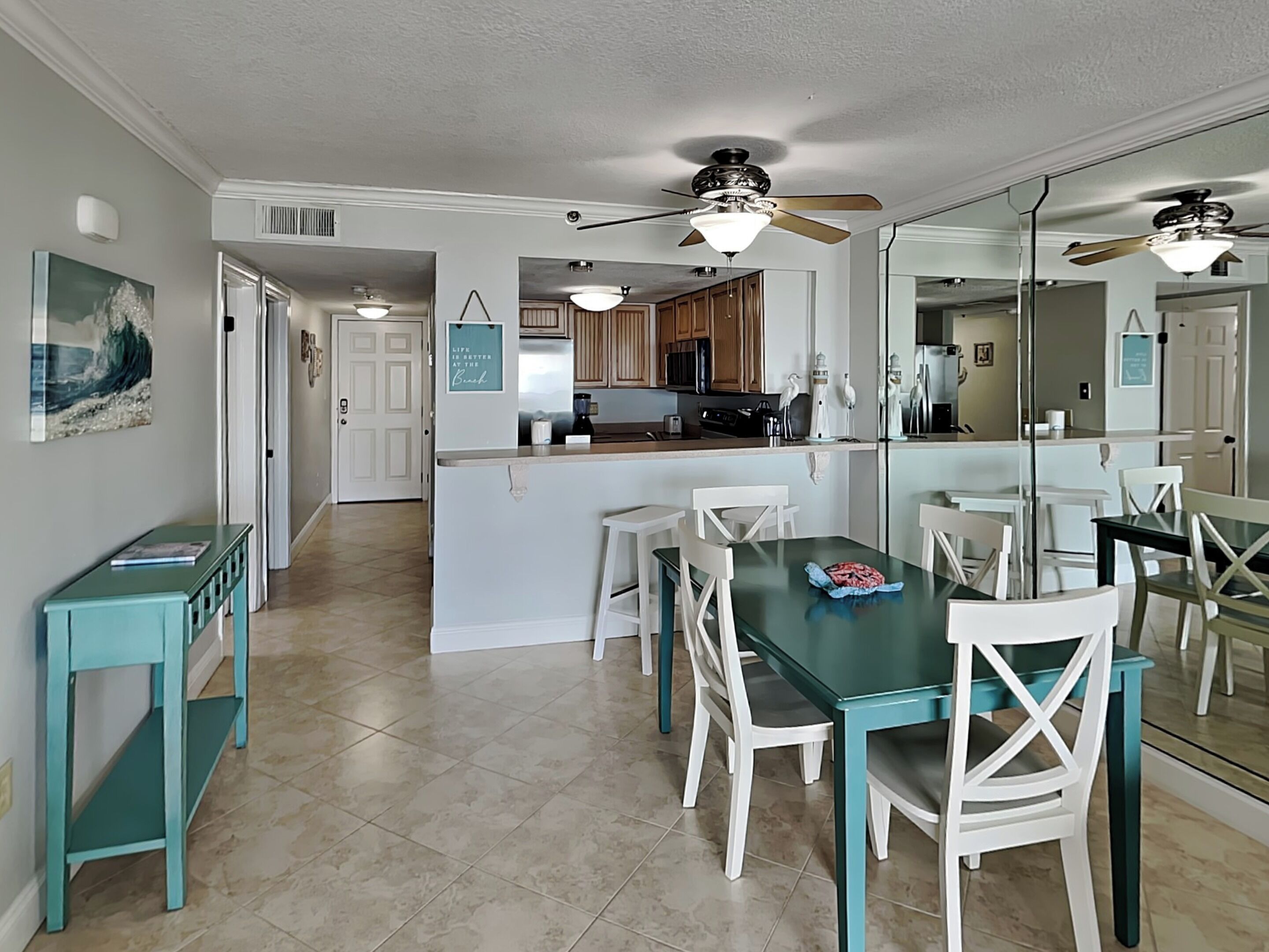 A spacious kitchen with a central island, white chairs, and a dining table.