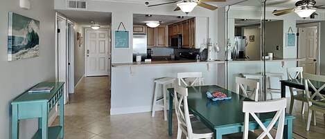 A spacious kitchen with a central island, white chairs, and a dining table.