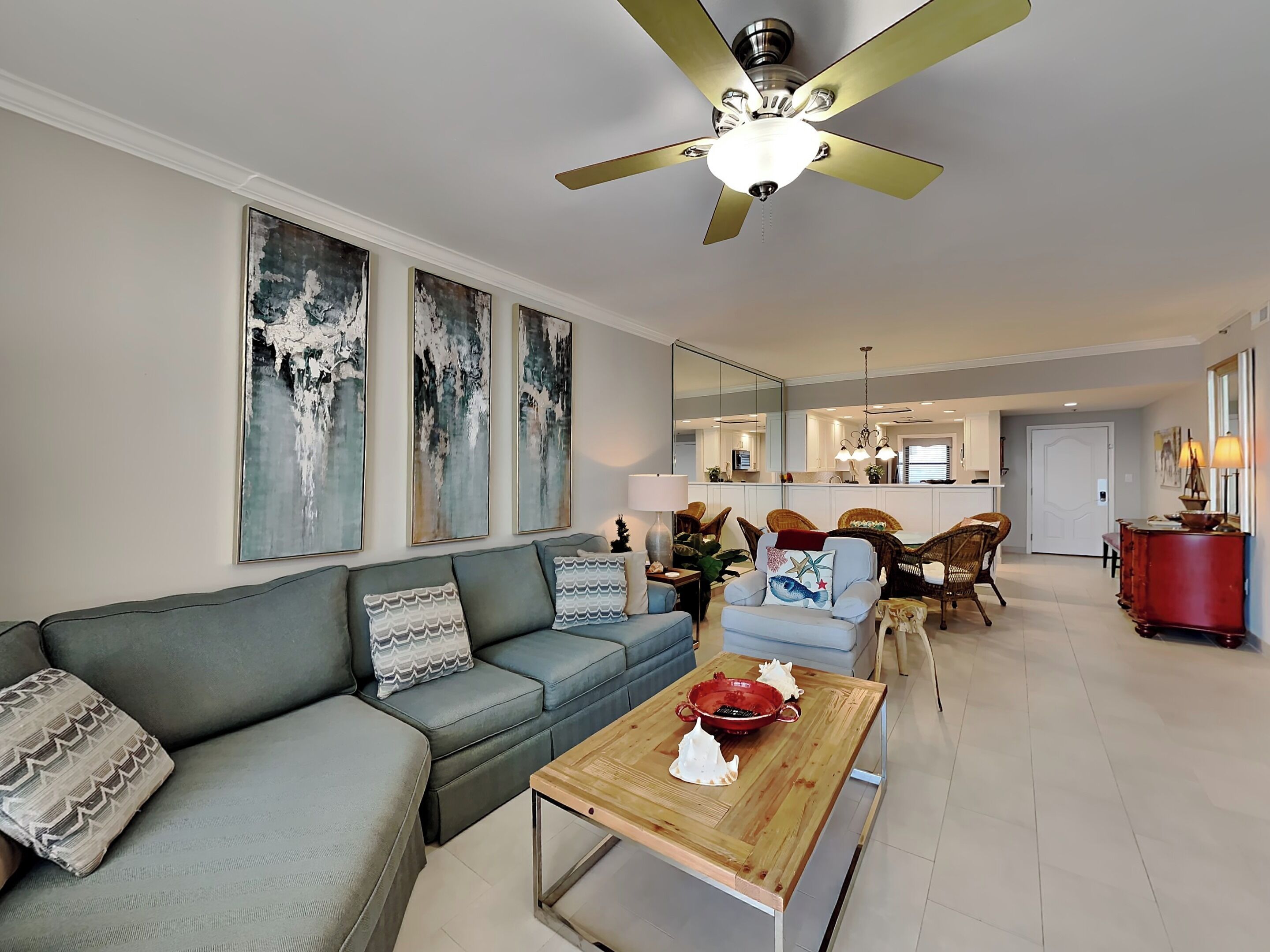 A modern living room with a grey sofa, a wooden coffee table, and a ceiling fan.