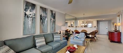A modern living room with a grey sofa, a wooden coffee table, and a ceiling fan.
