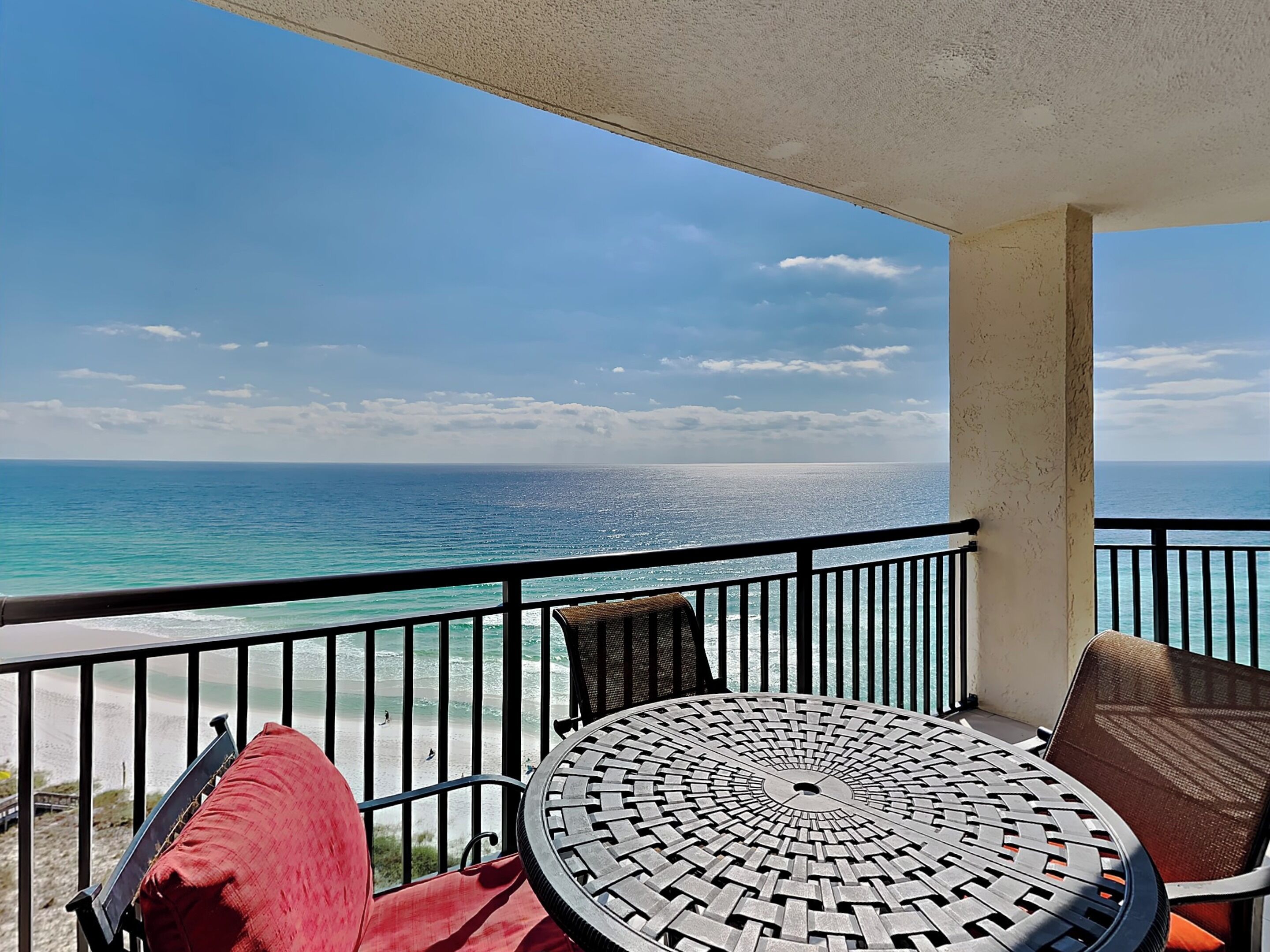 A balcony with a view of the ocean, a round table, and two chairs.