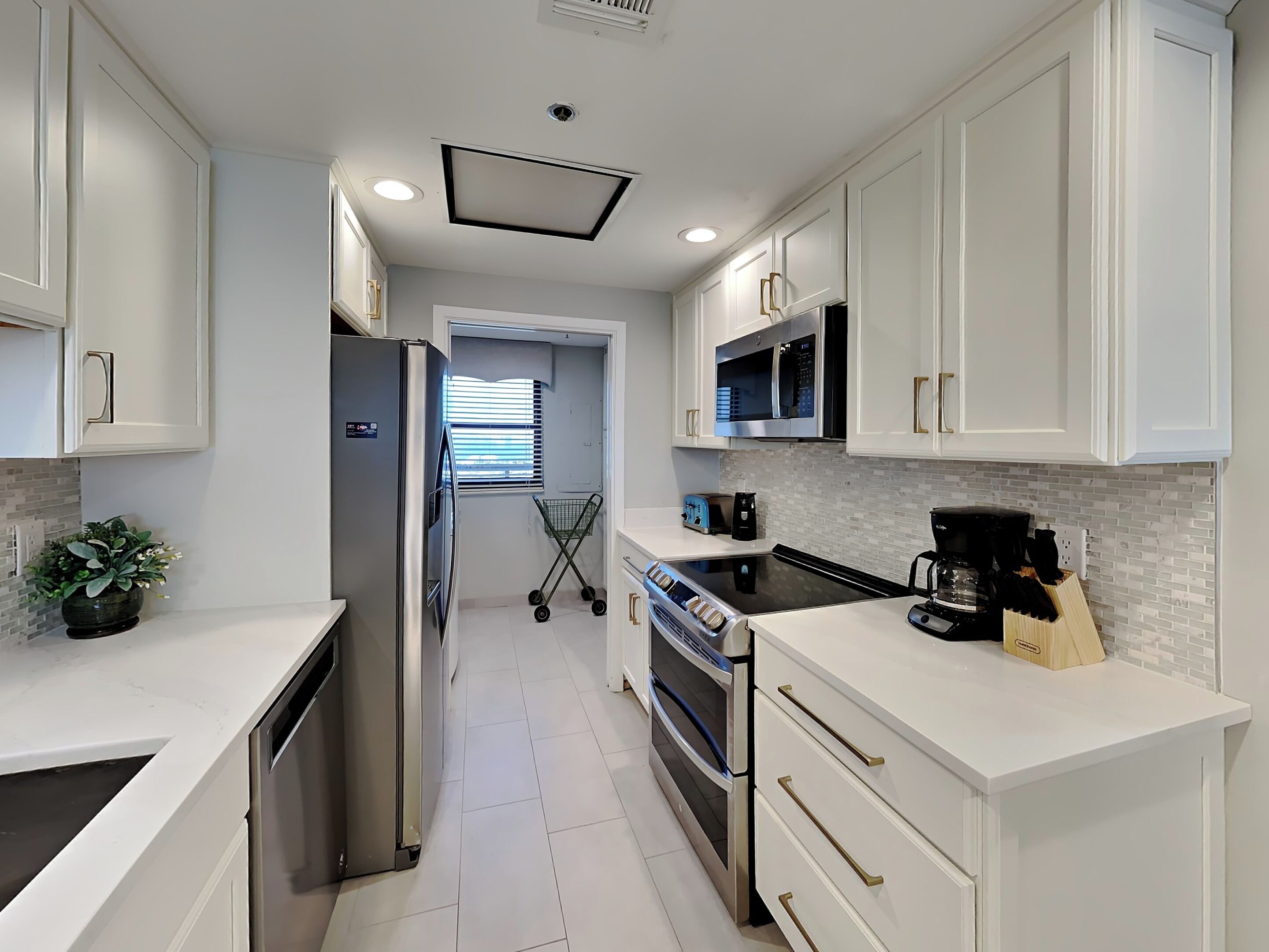 A modern kitchen with white cabinetry, stainless steel appliances, and a tiled backsplash.