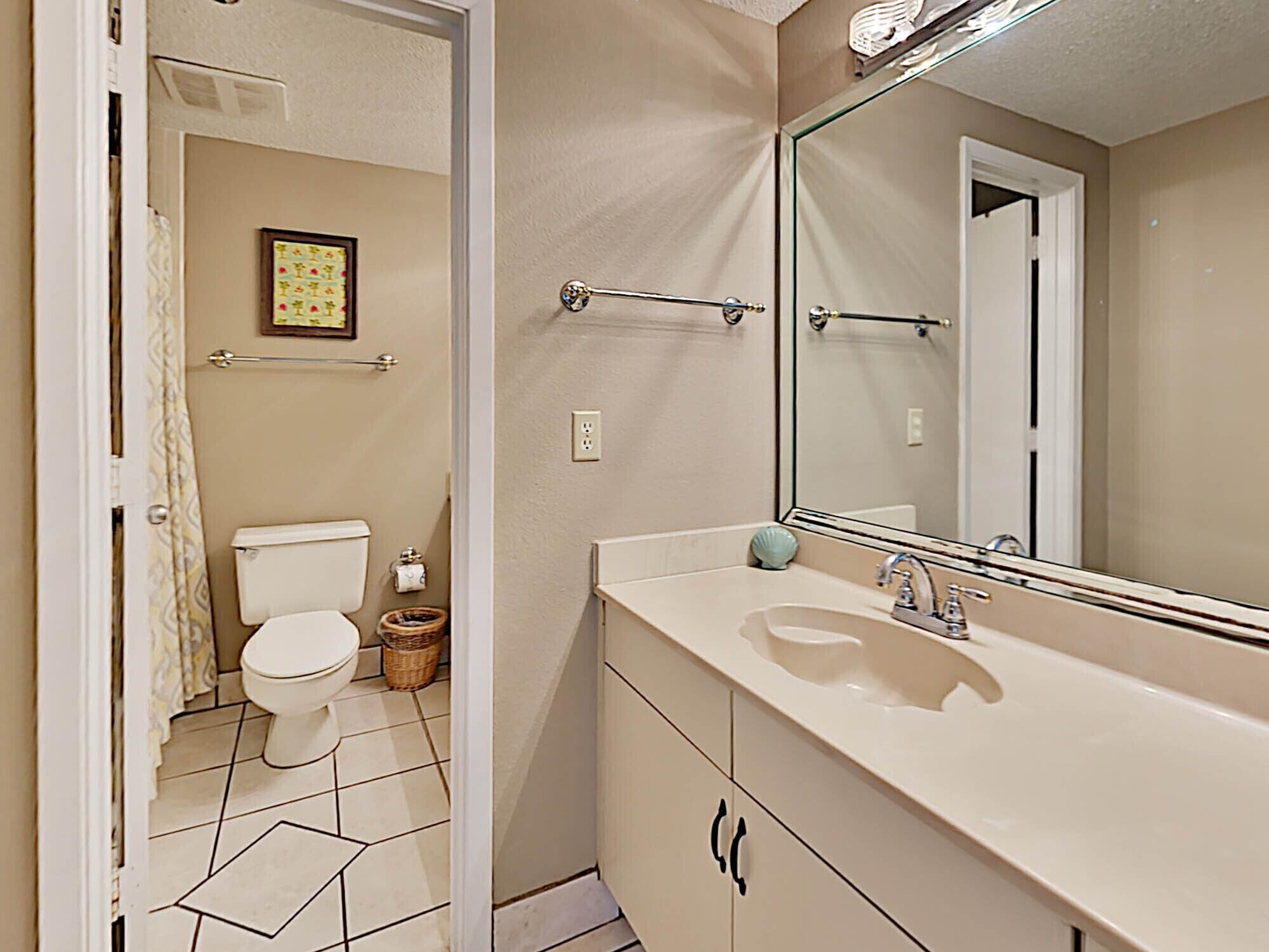 A bathroom with a toilet, sink, and mirror.