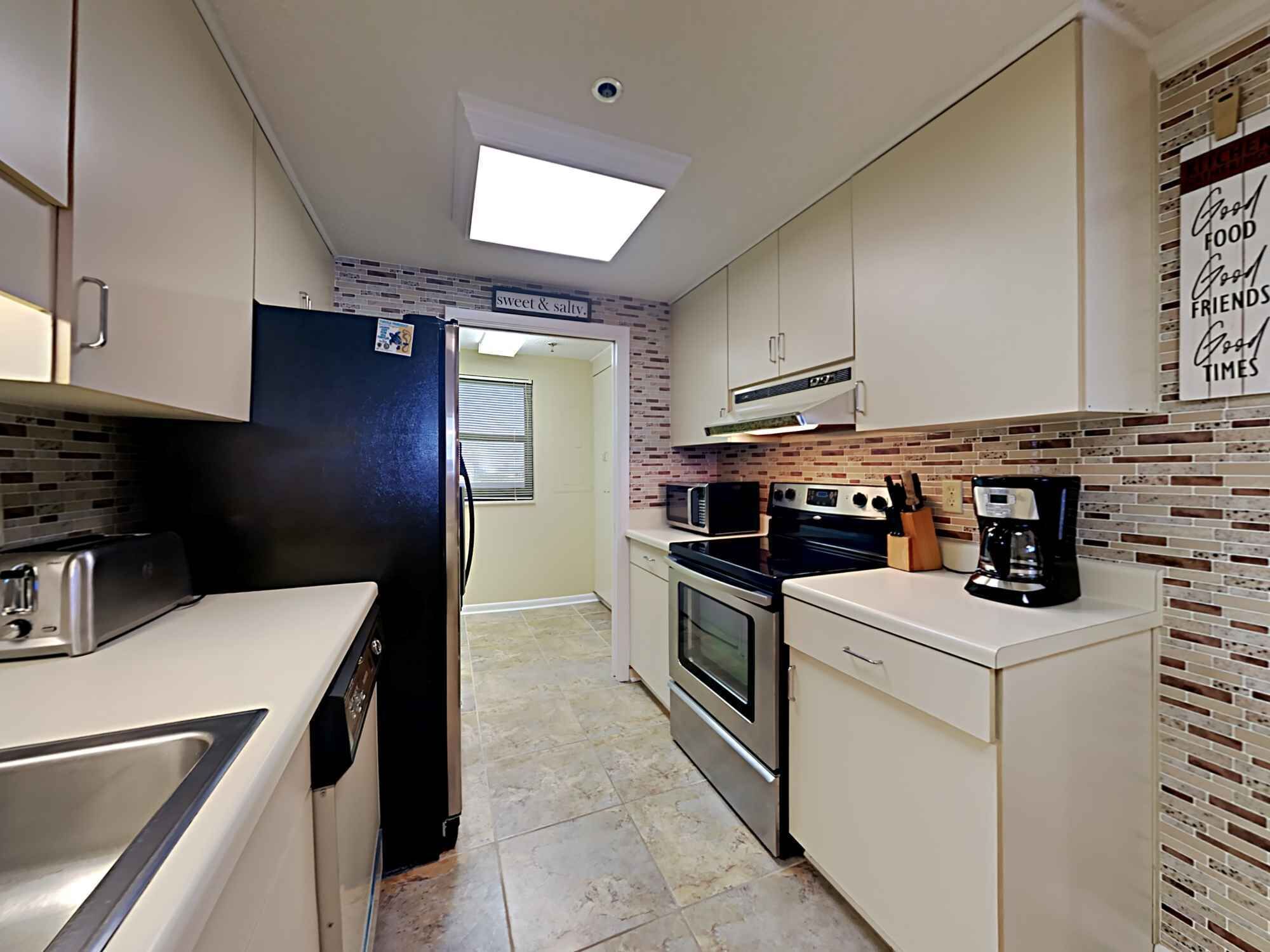 Una cocina compacta equipada con refrigerador, microondas, estufa y cafetera.