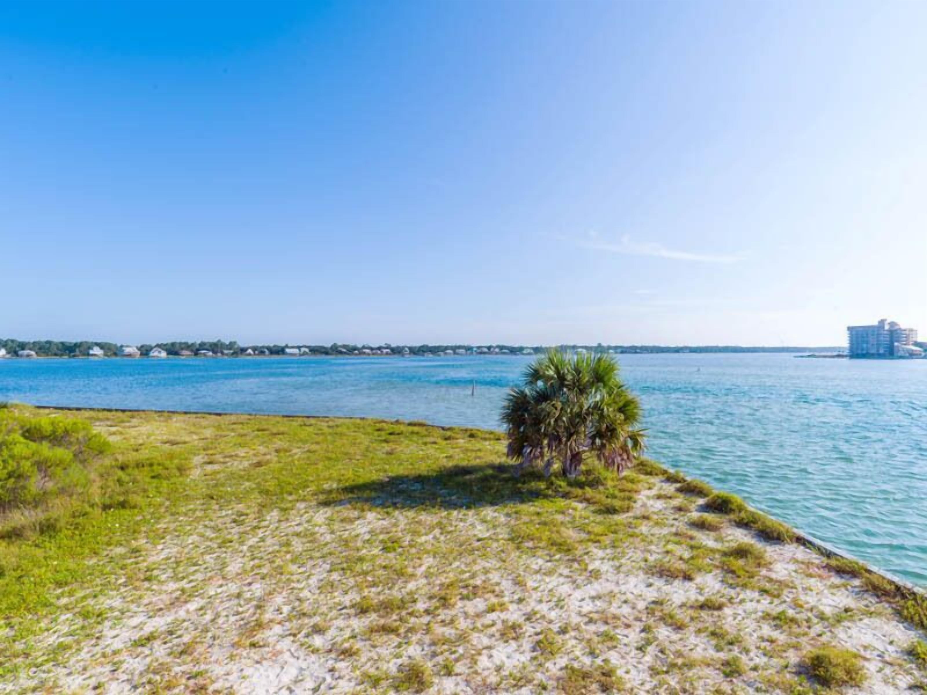 A coastal view with a clear sky, a body of water, and a distant building.