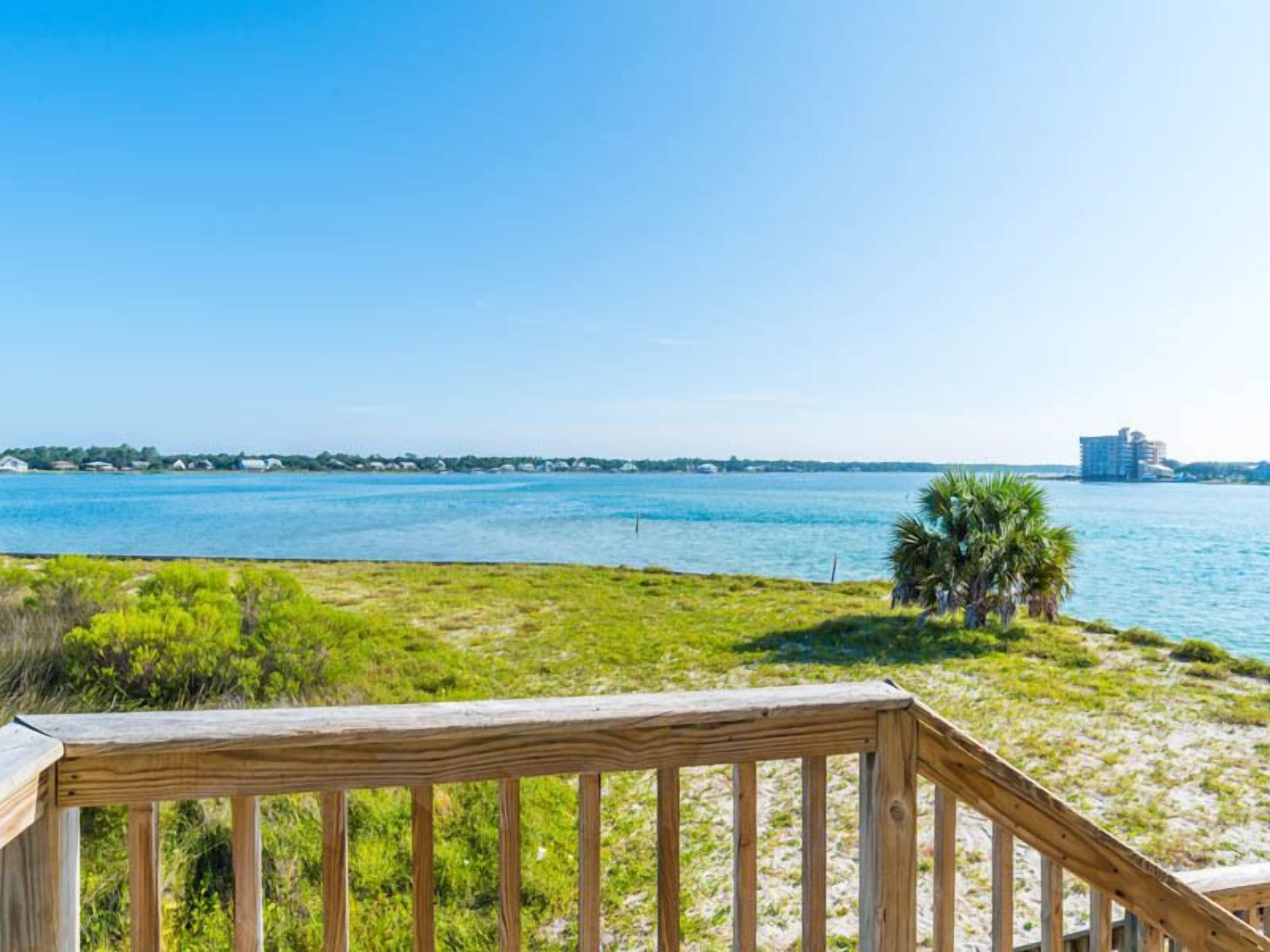 A wooden deck overlooking a body of water with distant buildings.