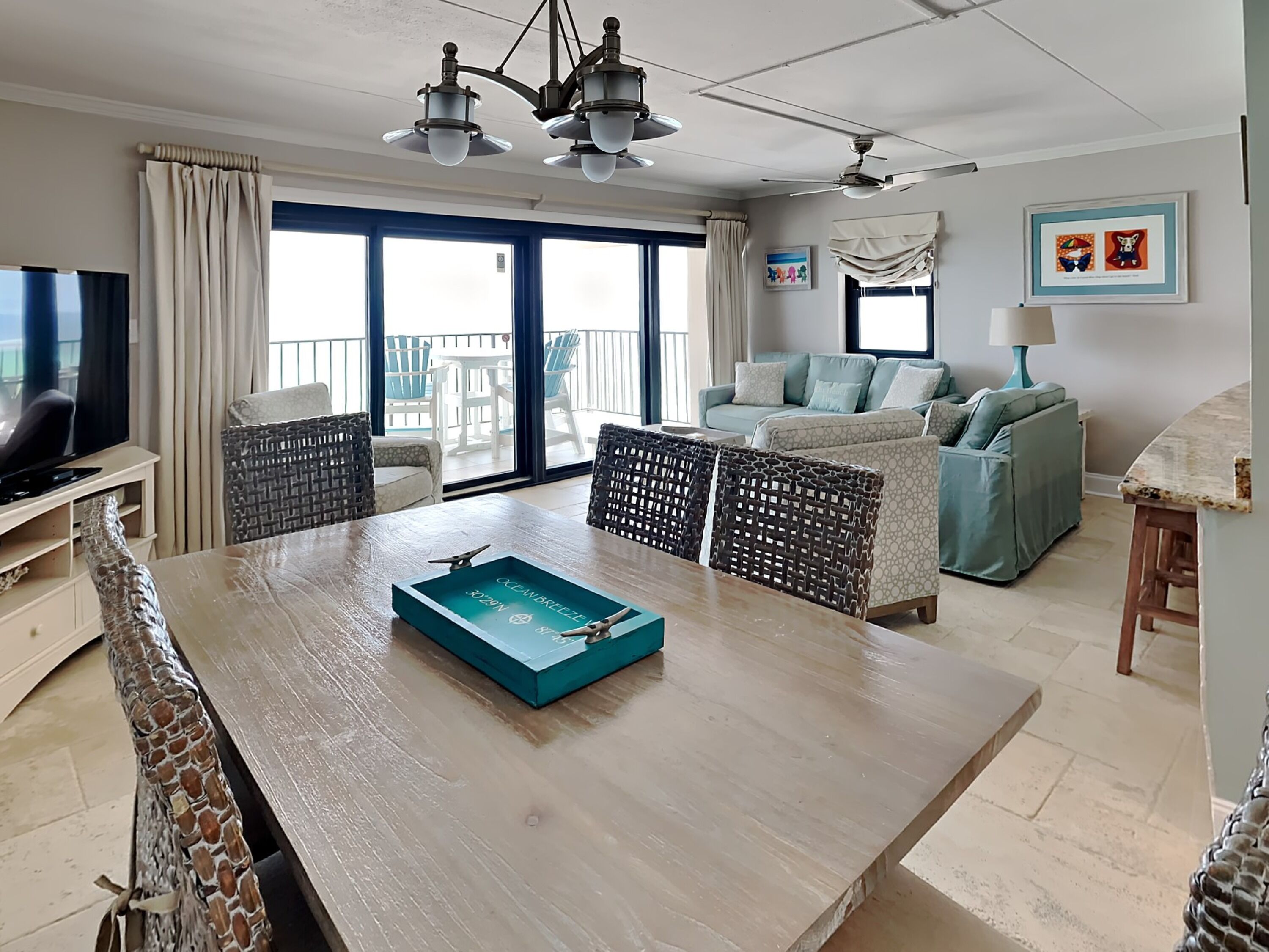 A spacious living area with a wooden coffee table, wicker chairs, a sofa, and a television.