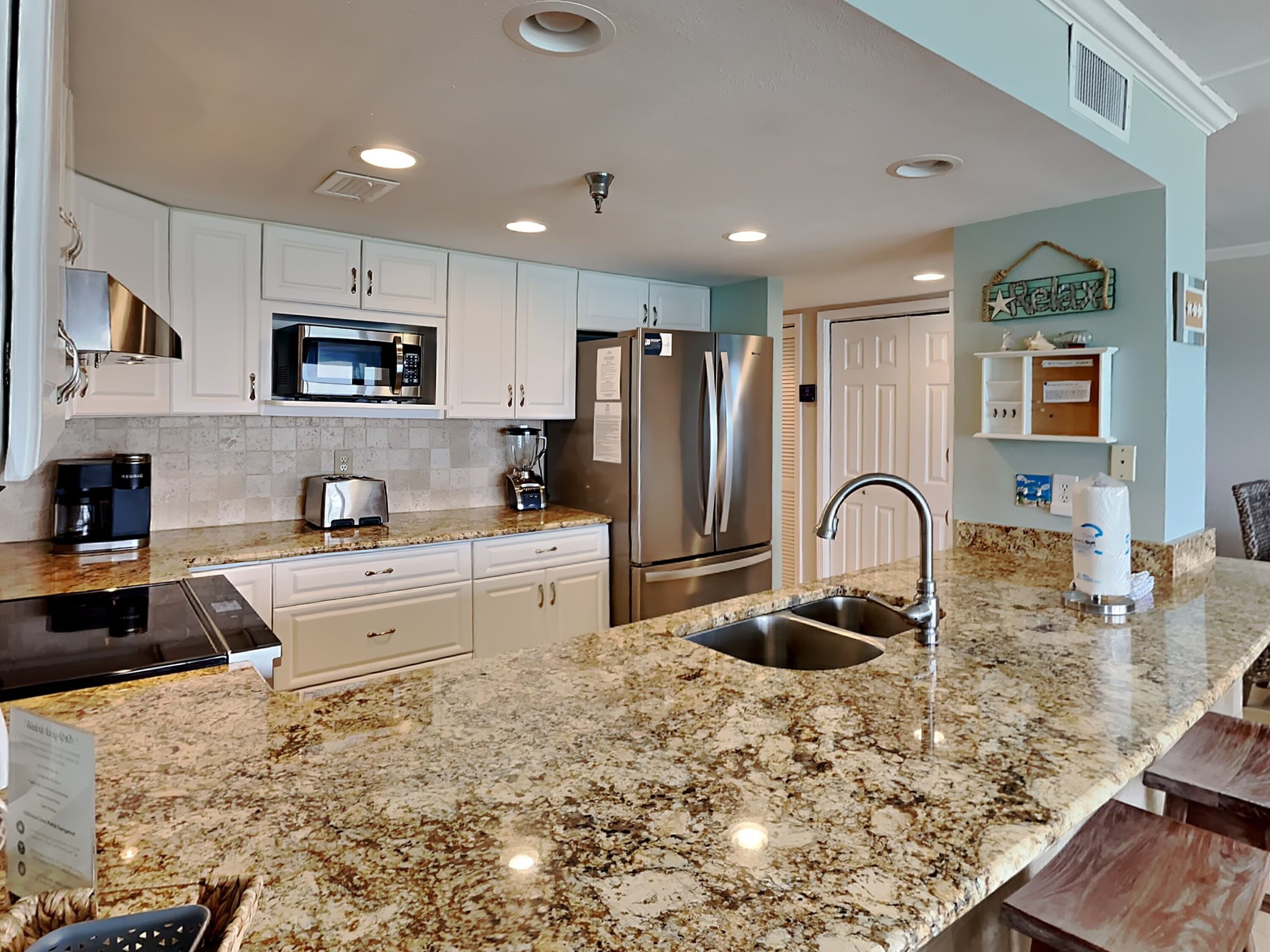 A modern kitchen with granite countertops, stainless steel appliances, and white cabinetry.