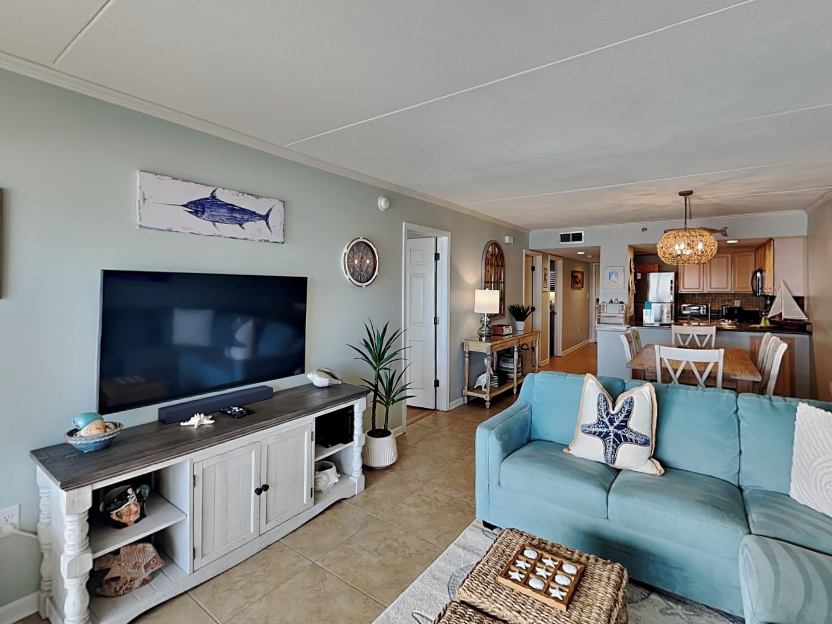 Una sala de estar con televisor, sofá y comedor.