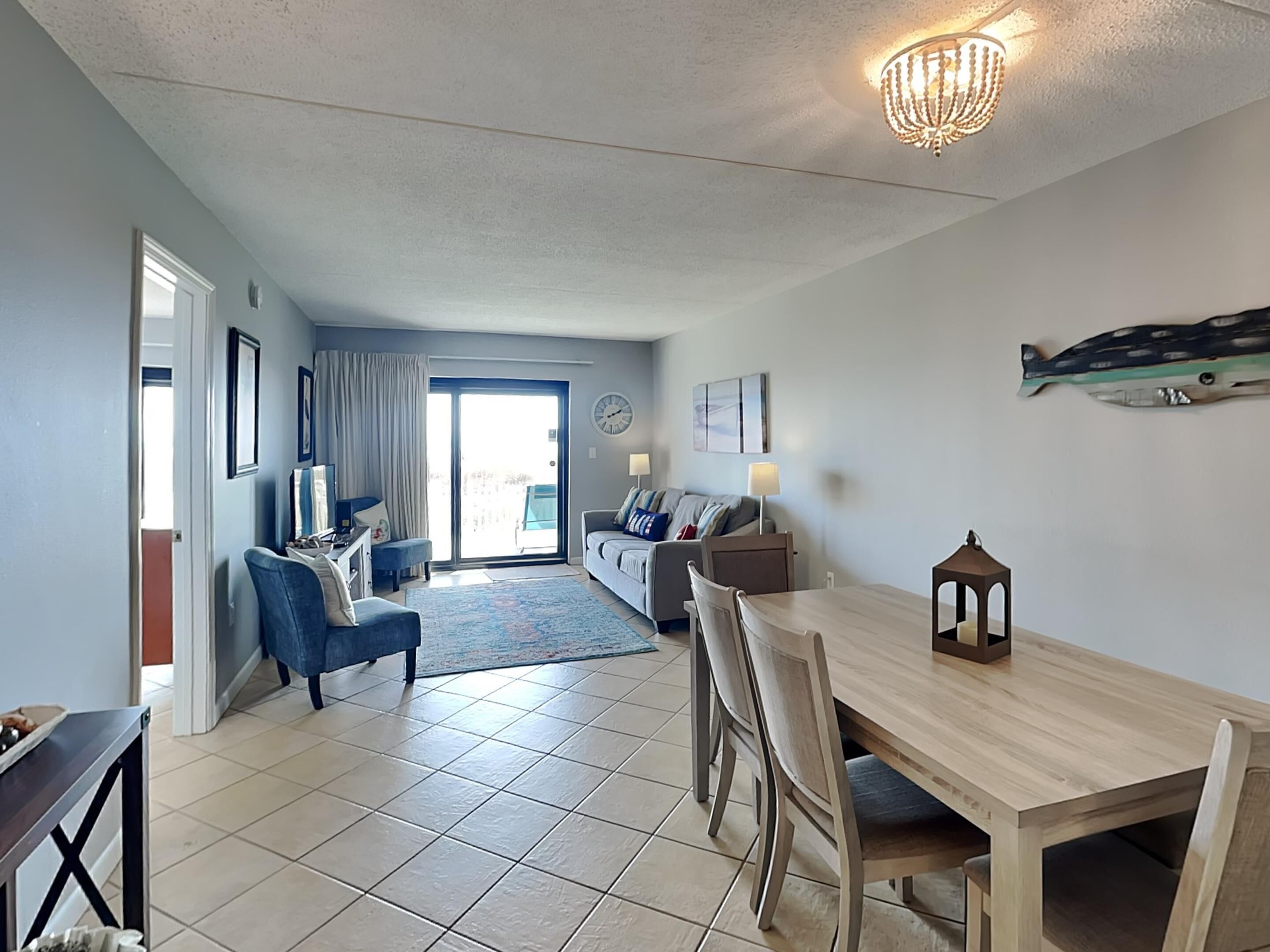 A spacious living area with a dining table, sofas, and a chandelier.