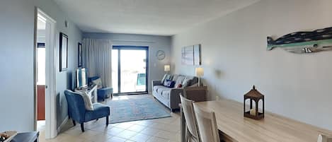 A spacious living area with a dining table, sofas, and a chandelier.