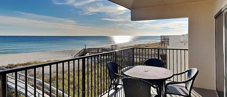A balcony with a view of the beach and ocean.
