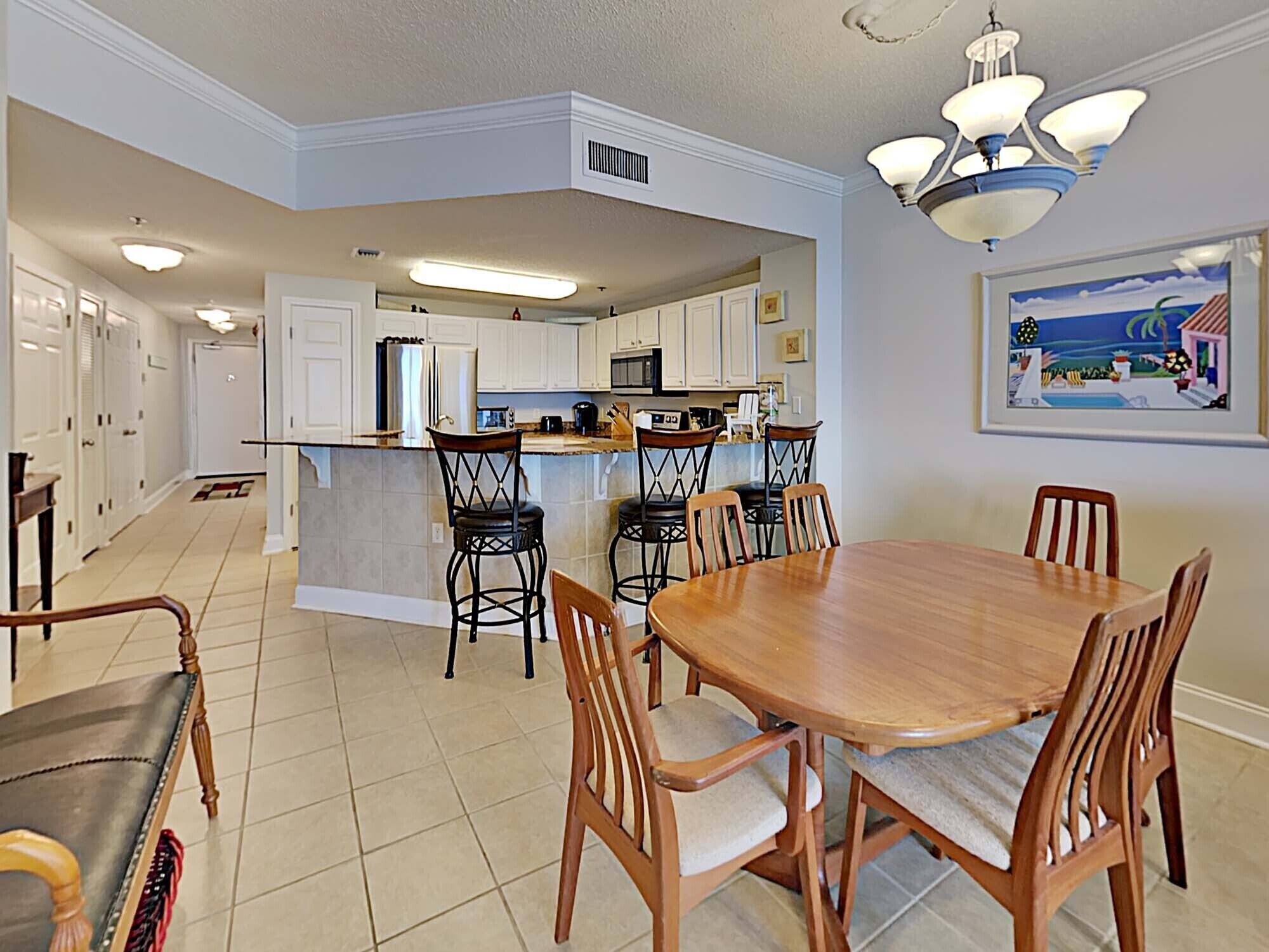 A spacious kitchen with white cabinets, a central island, and bar stools.