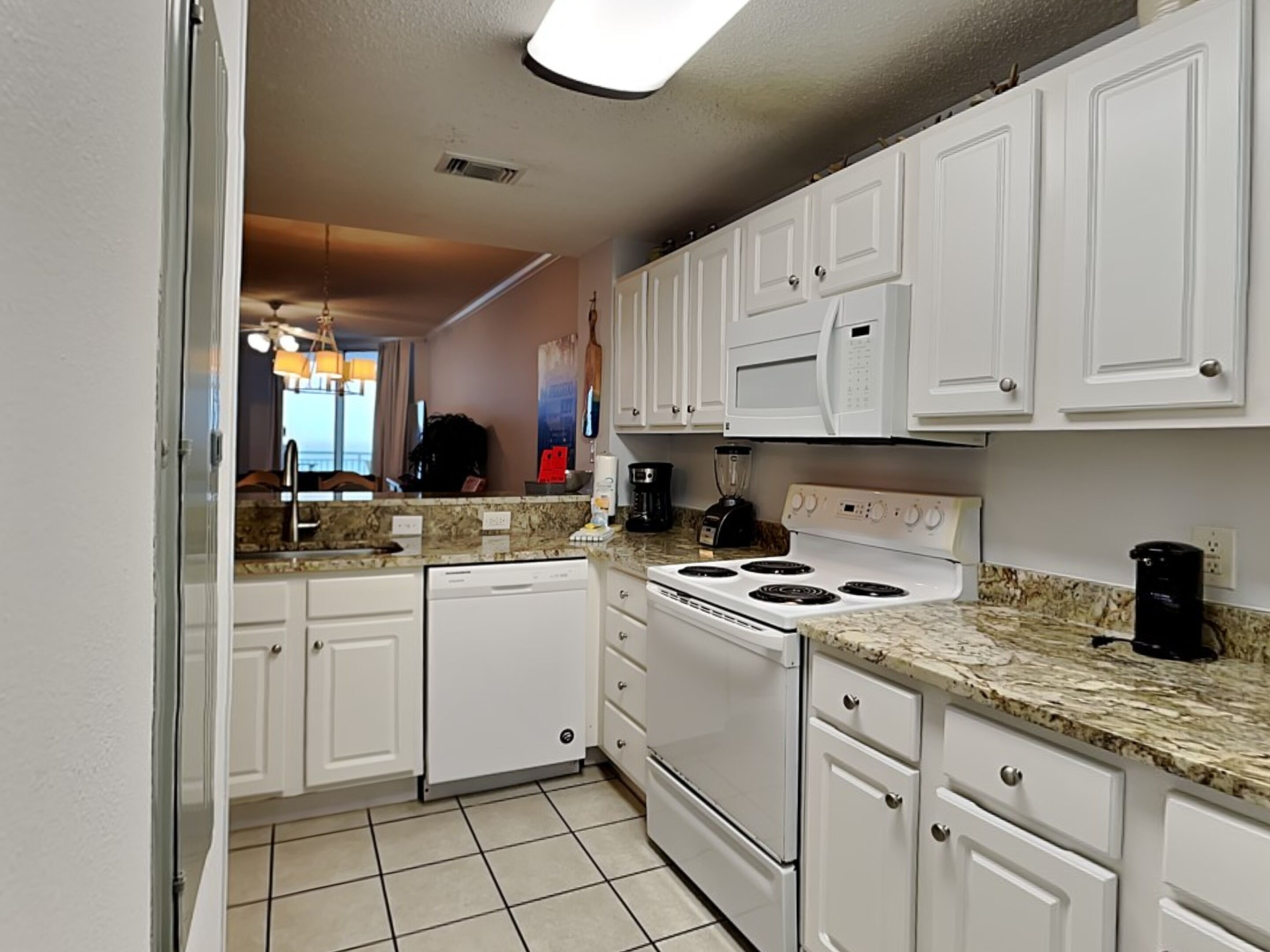 A kitchen with white cabinets, a stove, a dishwasher, and a granite countertop.