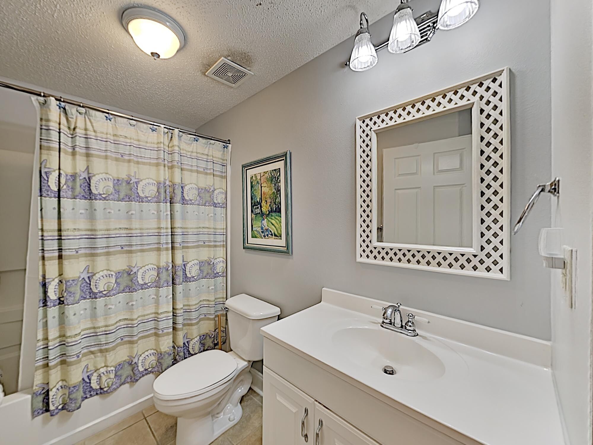 A bathroom with a toilet, sink, and shower curtain.
