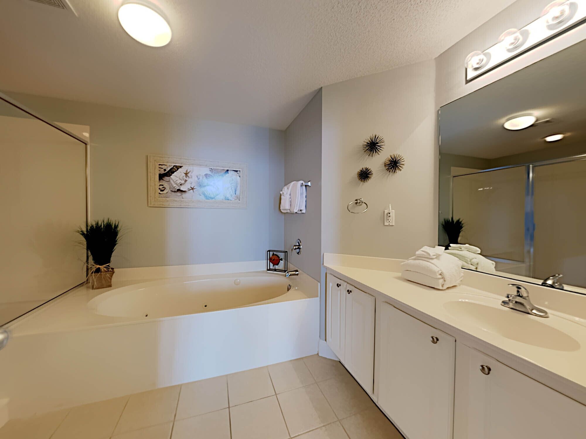 A modern bathroom with a bathtub, a large mirror, and a vanity with a sink.