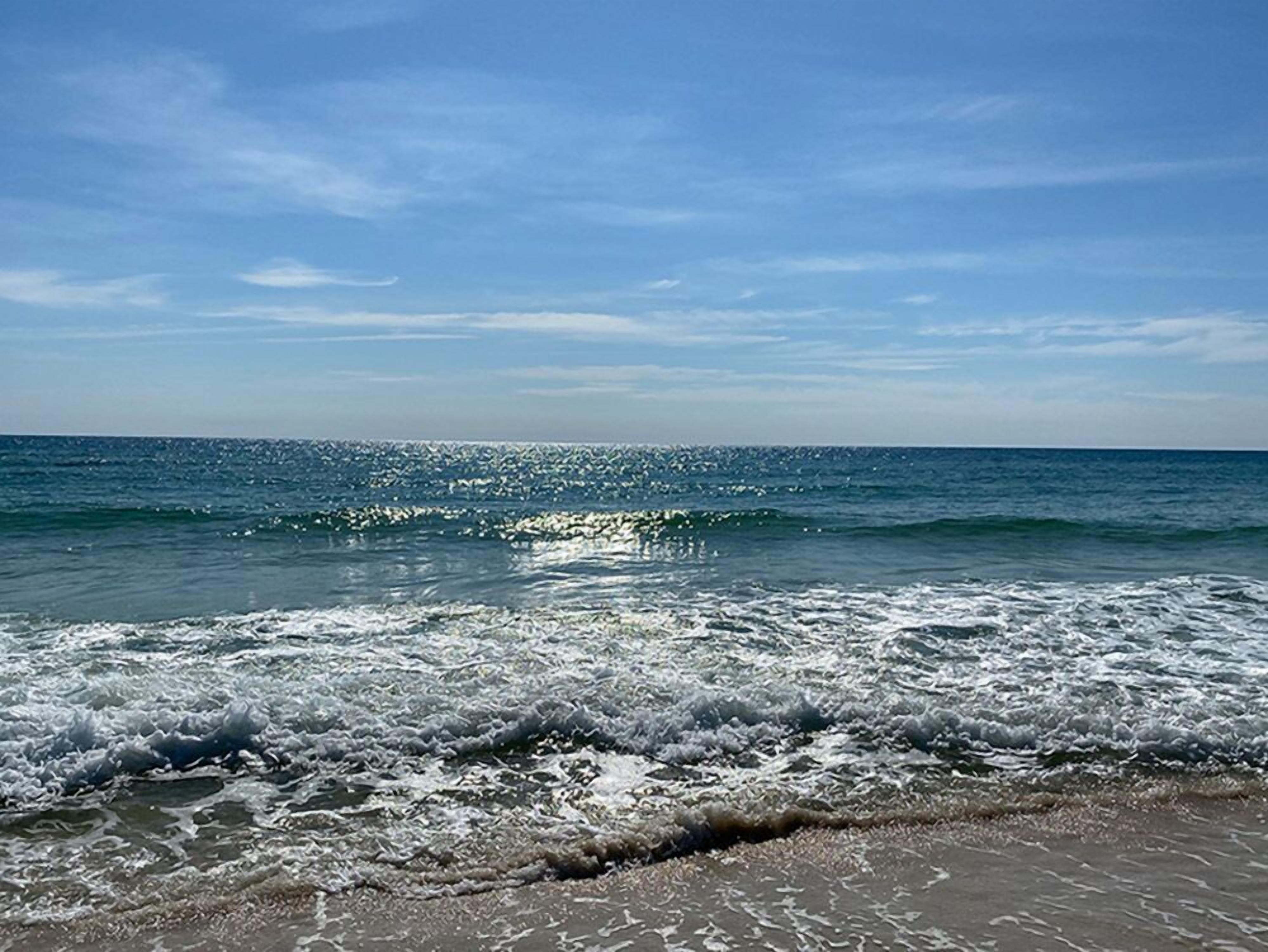 A beach with waves and a clear sky.