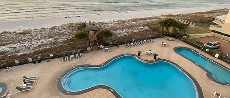 A pool area with a view of the beach and ocean.